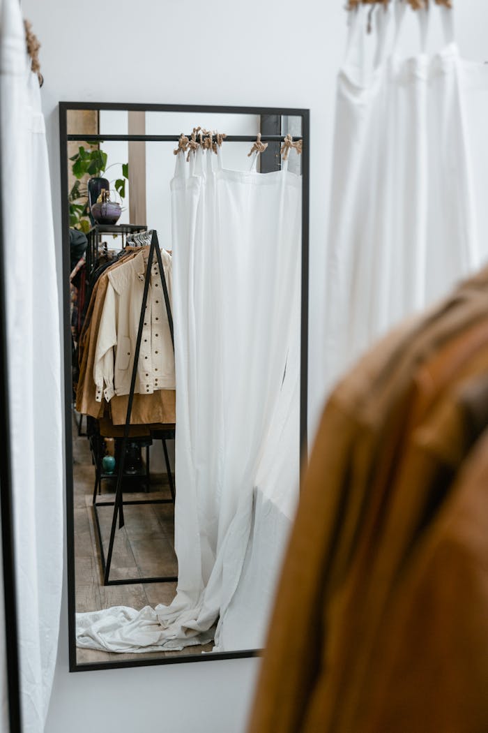 services-02 Modern clothing boutique with fitting room mirror and hanging garments.
